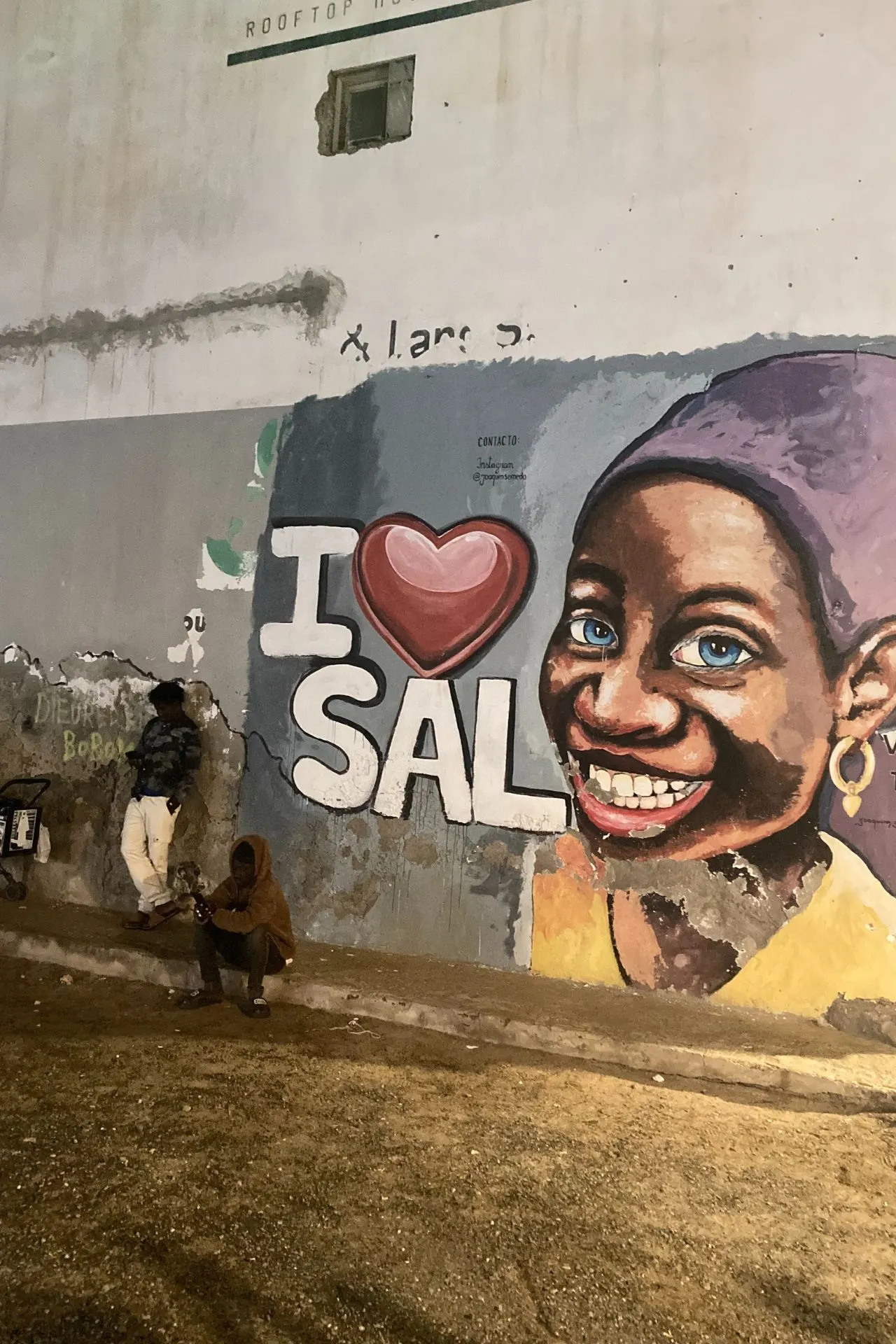 Grote muurschildering in Kaapverdië met beelden van sport, zee en de Kaapverdische vlag, geschilderd op een felgekleurde gevel langs een straat in Santa Maria. Deze kunstuiting weerspiegelt de trots en energie van het eiland en past bij een culturele reis Kaapverdië. Voor bezoekers die geïnteresseerd zijn in lokale bezienswaardigheden Kaapverdië toont dit beeld hoe street art, sport en de oceaan onderdeel zijn van het eilandleven.