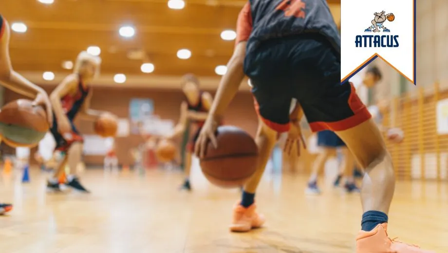 Foto genomen vanuit kikkerperspectief, jongeren spelen basketbal in een gymzaal bij basketbalvereniging Attacus, met een energieke en dynamische sfeer.