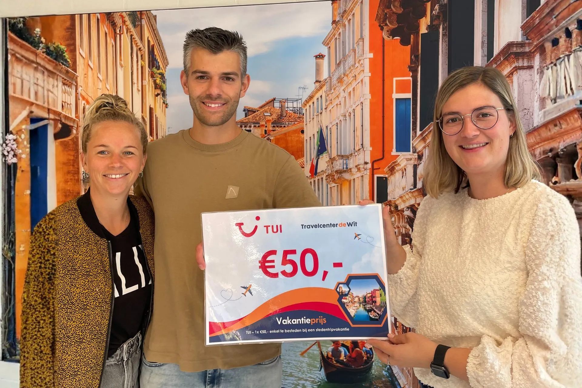 Koppel ontvangt een TUI-voucher van €50 uit handen van een medewerkster van Travelcenter de Wit tijdens de winactie in Gemert.