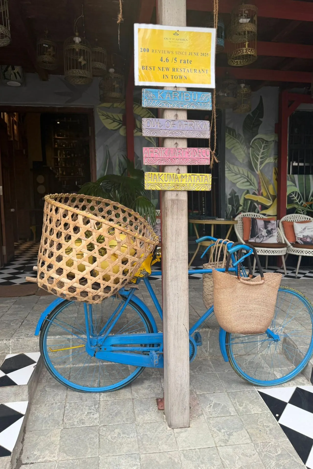 Kleurrijke fiets en typisch Zanzibar-bord met de tekst “Hakuna Matata” in het historische centrum van Stone Town. De hoofdstad van Zanzibar staat bekend om haar levendige cultuur, lokale winkeltjes, restaurants en unieke mix van Arabische, Afrikaanse en Europese invloeden.