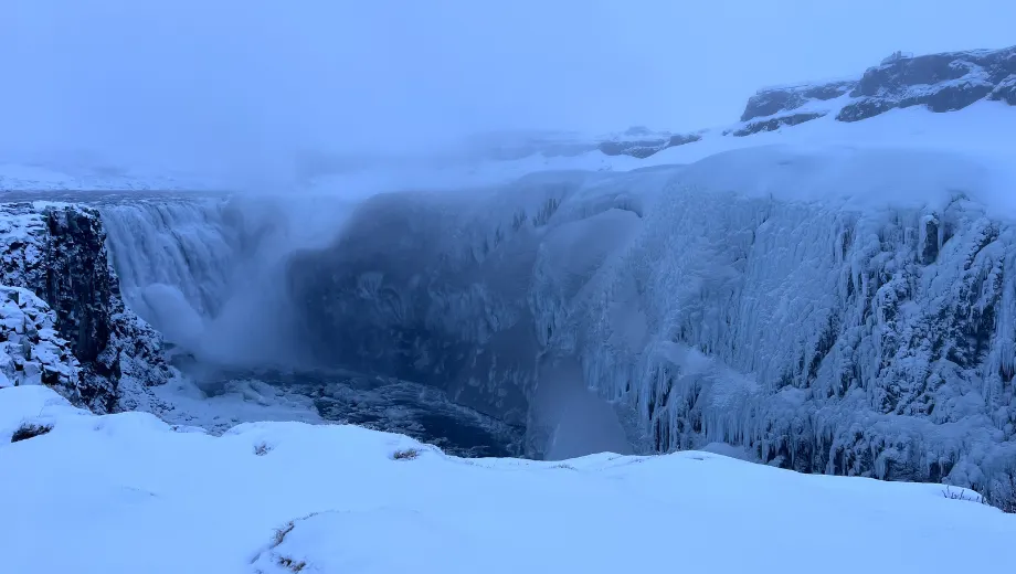 De Dettifoss‑waterval in Noord‑IJsland, omgeven door ijs en besneeuwde kliffen in de winter.
