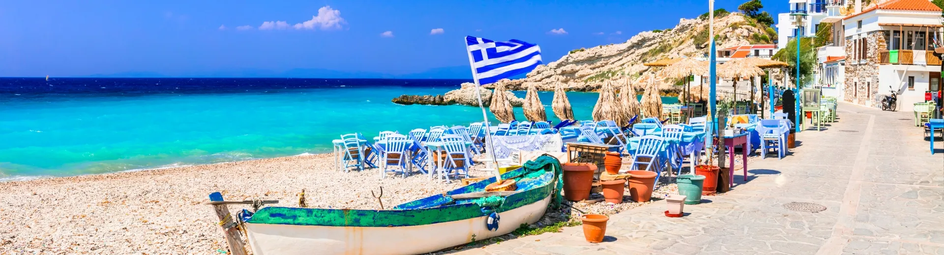 Boulevard langs het strand in Griekenland met uitzicht op helder, kleurrijk water in tropische tinten.