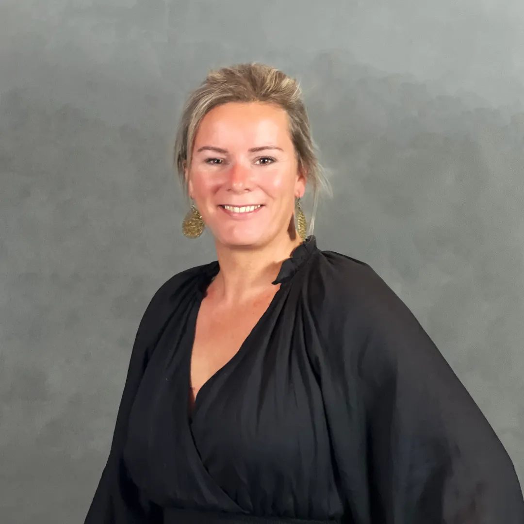  Portret van een persoon staand voor een neutrale grijze achtergrond, gekleed in een elegante zwarte blouse met lange, wijde mouwen en een diepe V-hals. Het kledingstuk heeft een zachte, vloeiende stof die een stijlvolle en formele uitstraling geeft. De setting is eenvoudig en minimalistisch, waardoor de focus volledig op de outfit ligt. Ideaal voor gebruik in zakelijke context, professionele presentatie of modegerelateerde content.