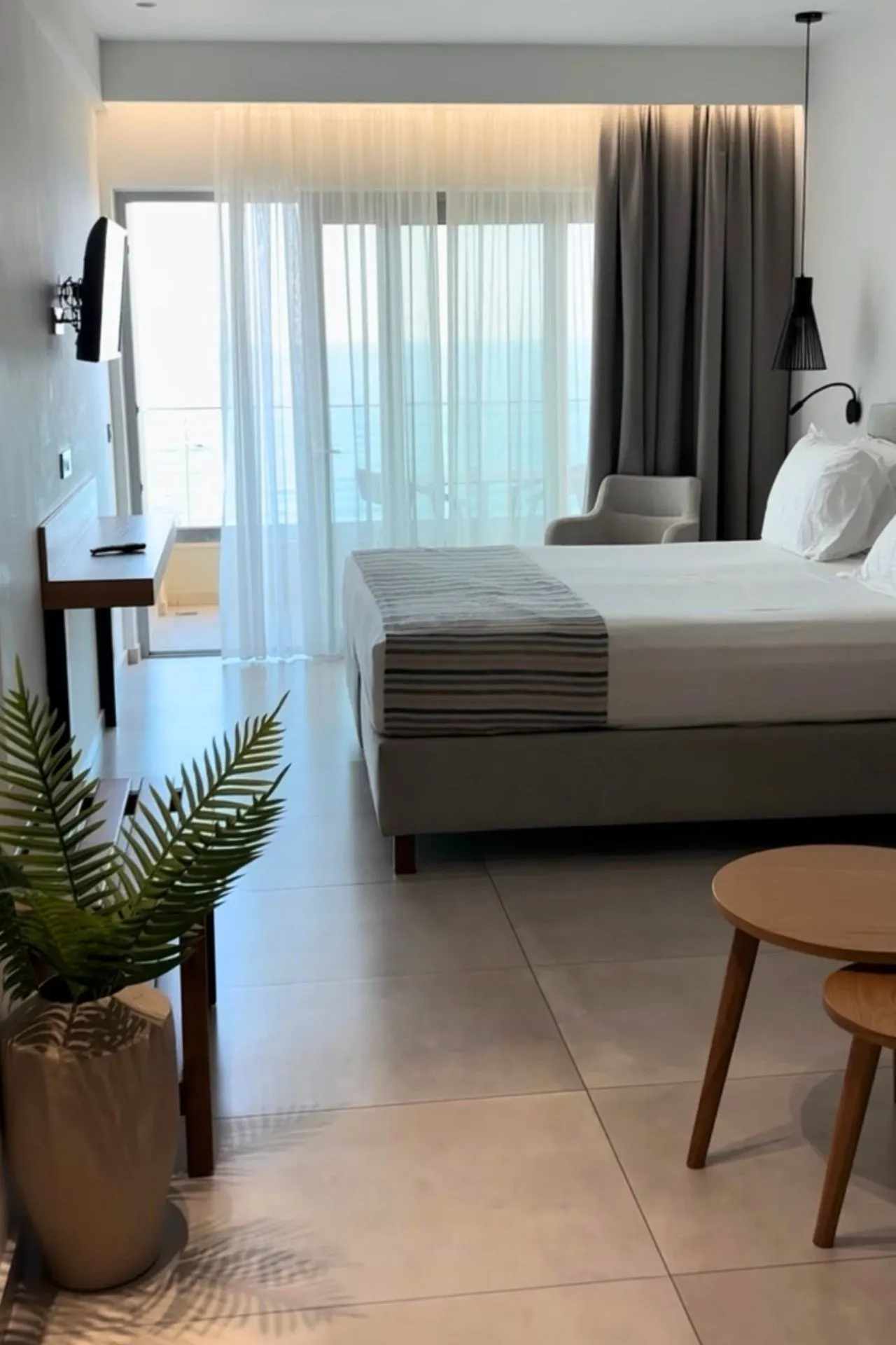 Moderne hotelkamer met groot bed, lichte gordijnen en balkon met uitzicht op zee in Batis Beach Hotel op Kreta.