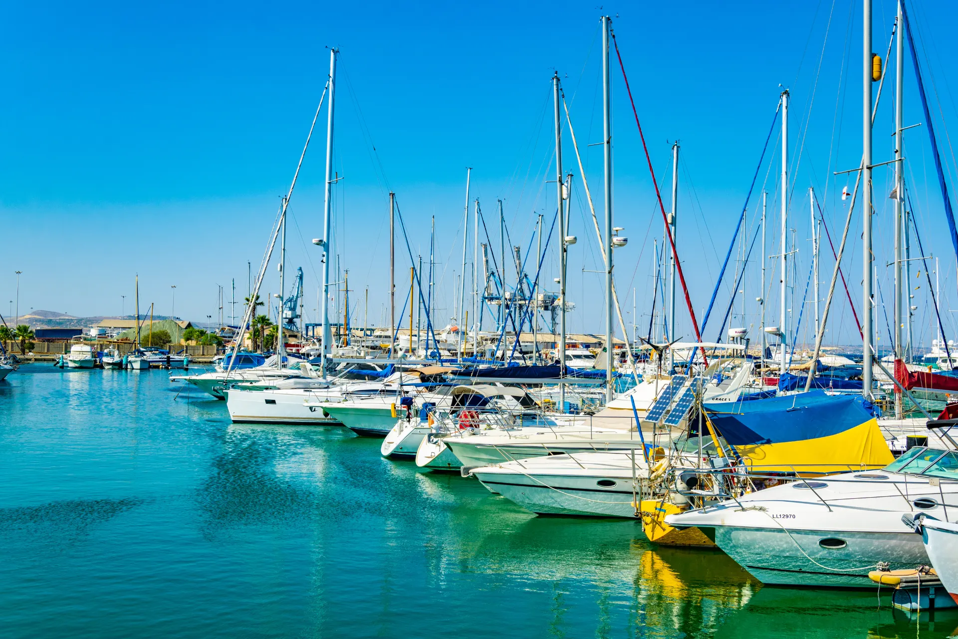 Zonnige dag aan de boulevard van Larnaca, waar zeilbootjes dobberen op kristalhelder water.