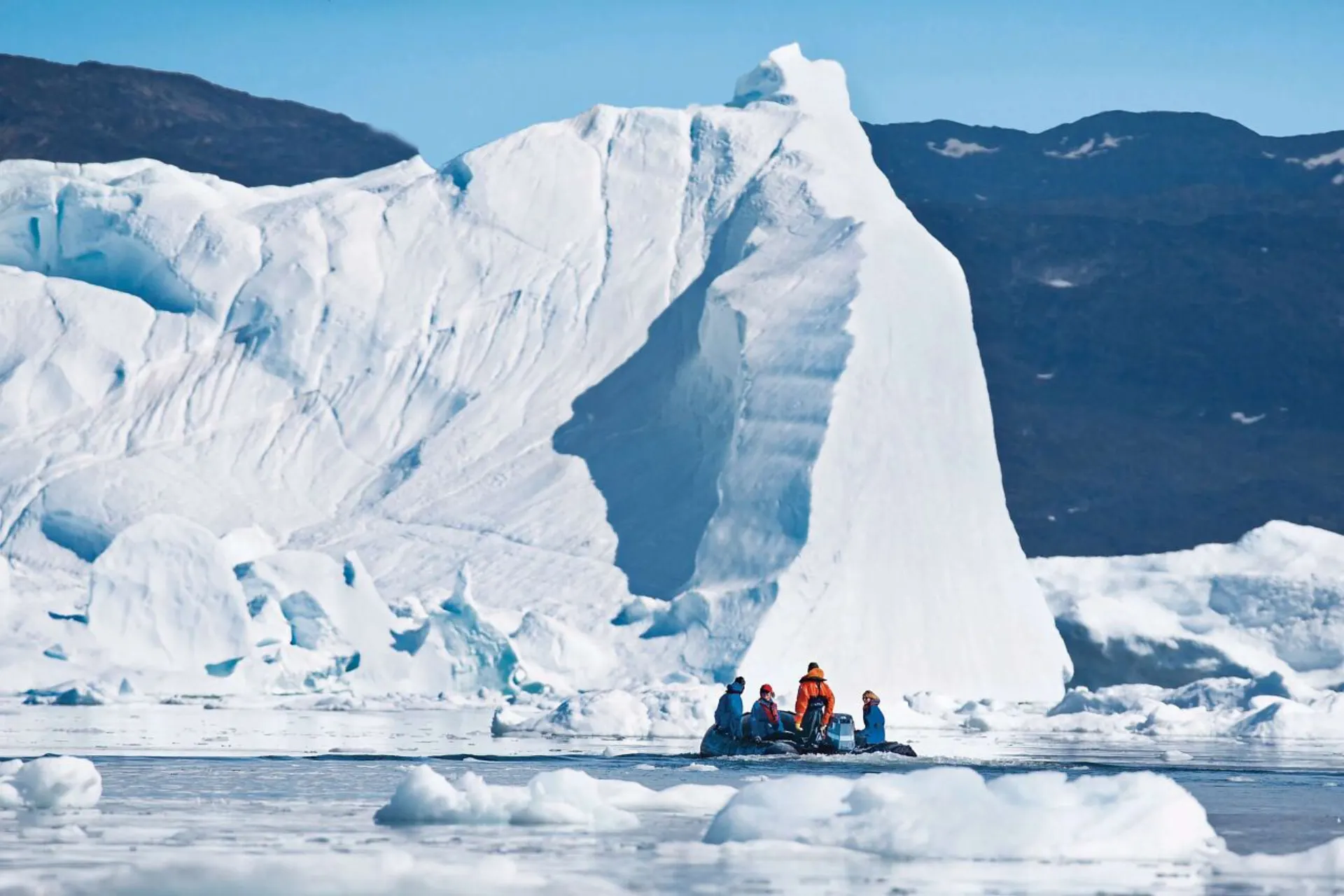Reusachtige ijsberg in Antarctica met een klein bootje op het water op de voorgrond.