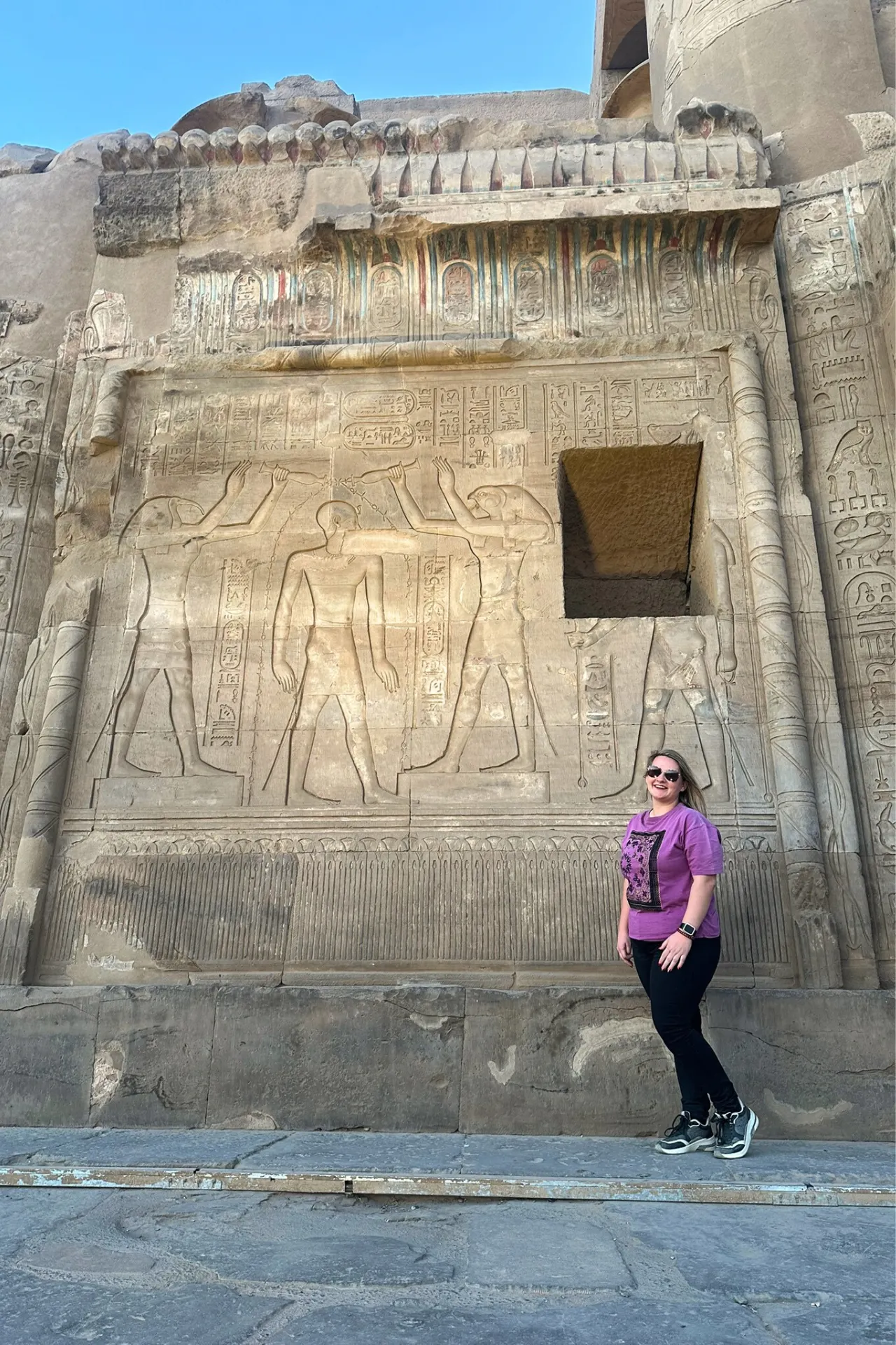 Naomi poseert lachend voor een oude muurgravering in Egypte.