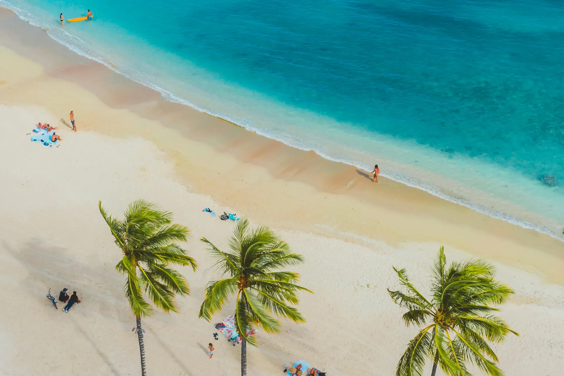 Rustig wit zandstrand bij Kendwa, Zanzibar, met mensen en palmbomen gezien vanuit de lucht.