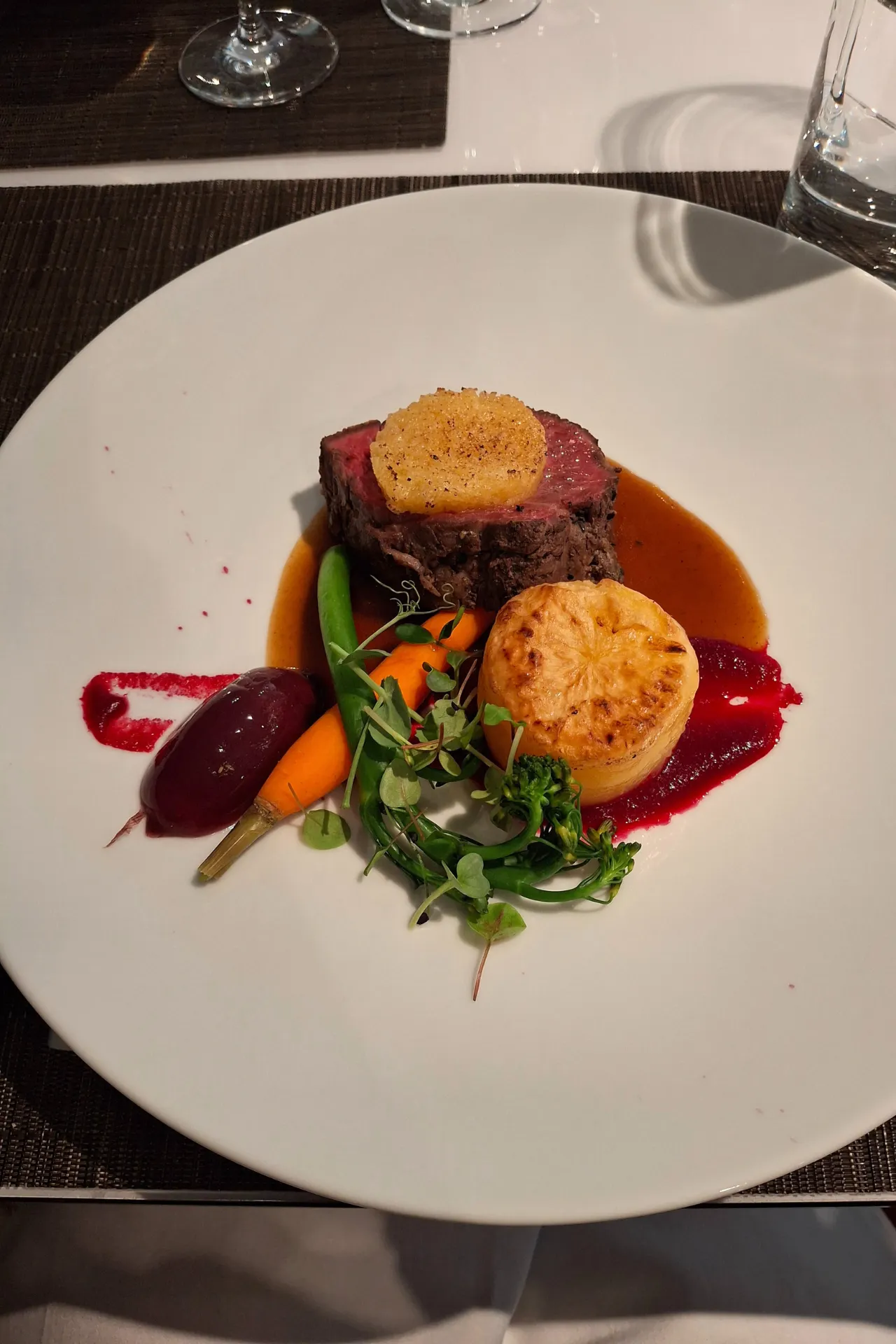Kleurrijk en culinair diner geserveerd op een rond wit bord, prachtig gepresenteerd.