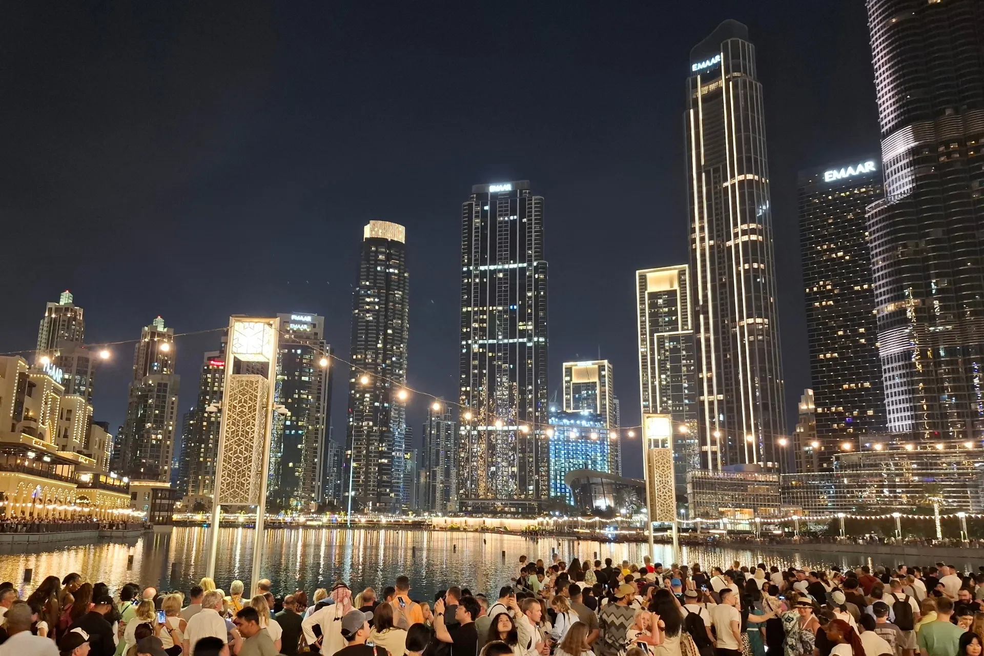 Avonduitzicht op de verlichte Burj Khalifa, met fonkelende lichten en de skyline van Dubai op de achtergrond.