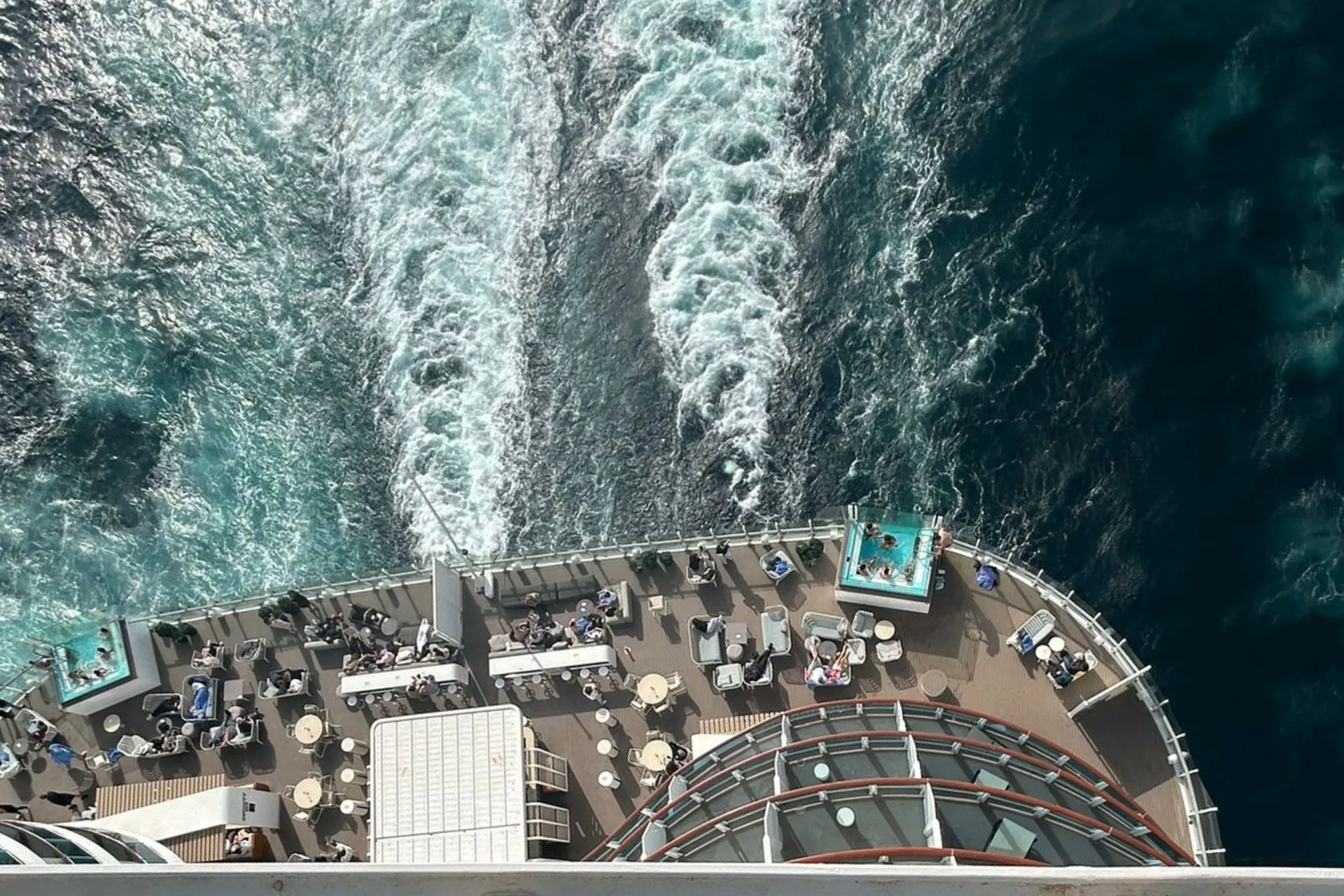 Bovendek van cruiseship Costa Toscana met zwembaden en ligbedden tijdens een zeedag op zee
