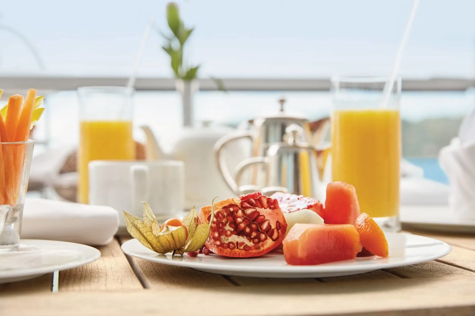  Luxe ontbijt met verse jus, vers fruit en fijne details geserveerd op het dek van een Hapag Lloyd cruiseschip.