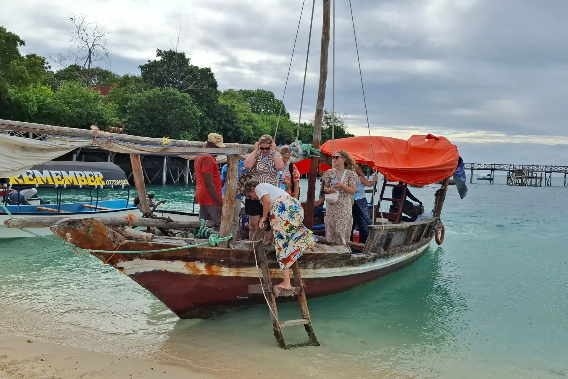 Bezoekers stappen vanaf een traditionele houten boot aan wal op Prison Island bij Zanzibar. Deze populaire excursie combineert een boottocht over de Indische Oceaan met ontmoetingen met eeuwenoude reuzenschildpadden en een bezoek aan een eiland met een rijke koloniale geschiedenis.