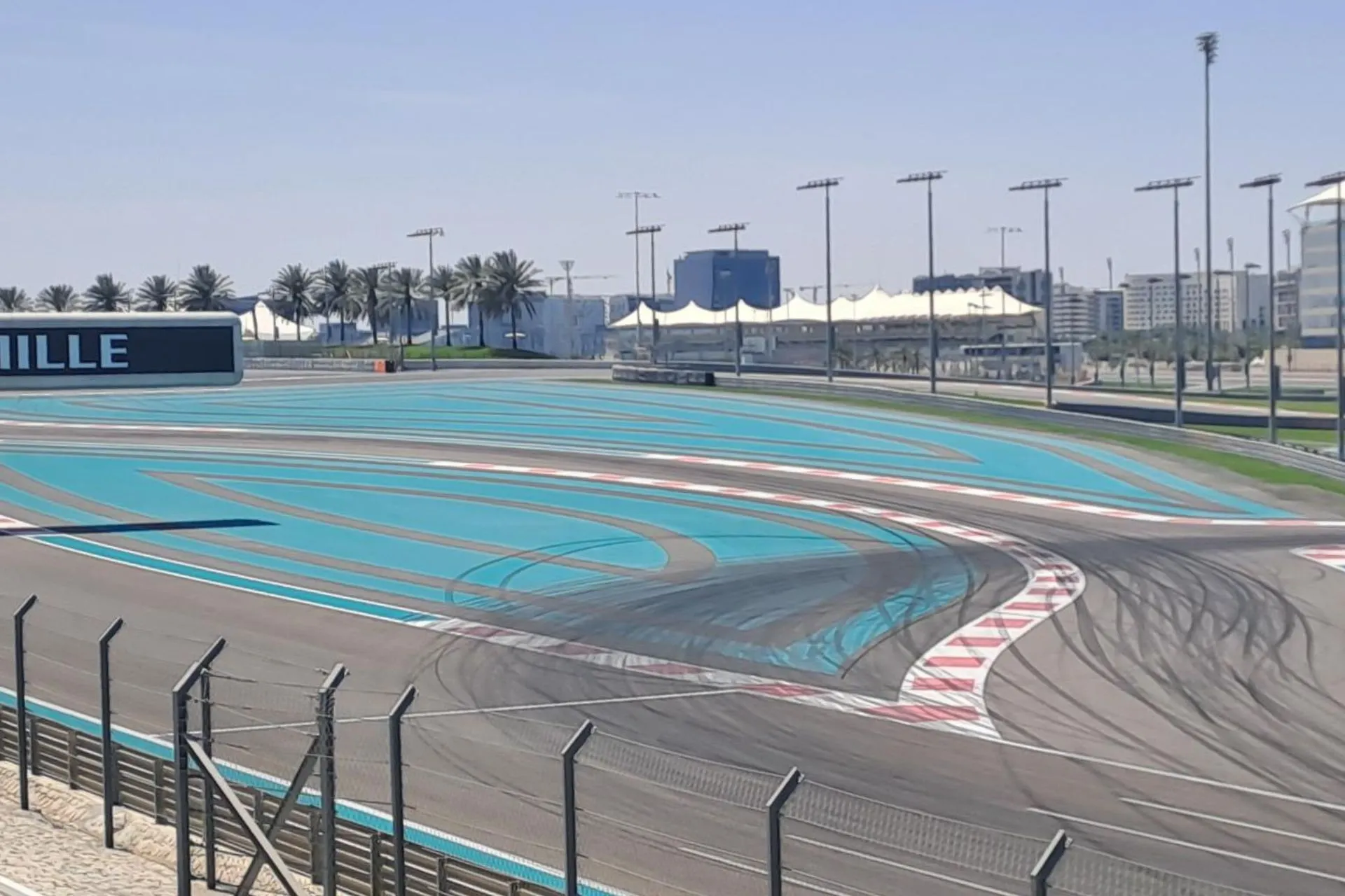 Het Yas Marina Circuit in Abu Dhabi met blauwe racebanen en zicht op palmbomen en moderne gebouwen.