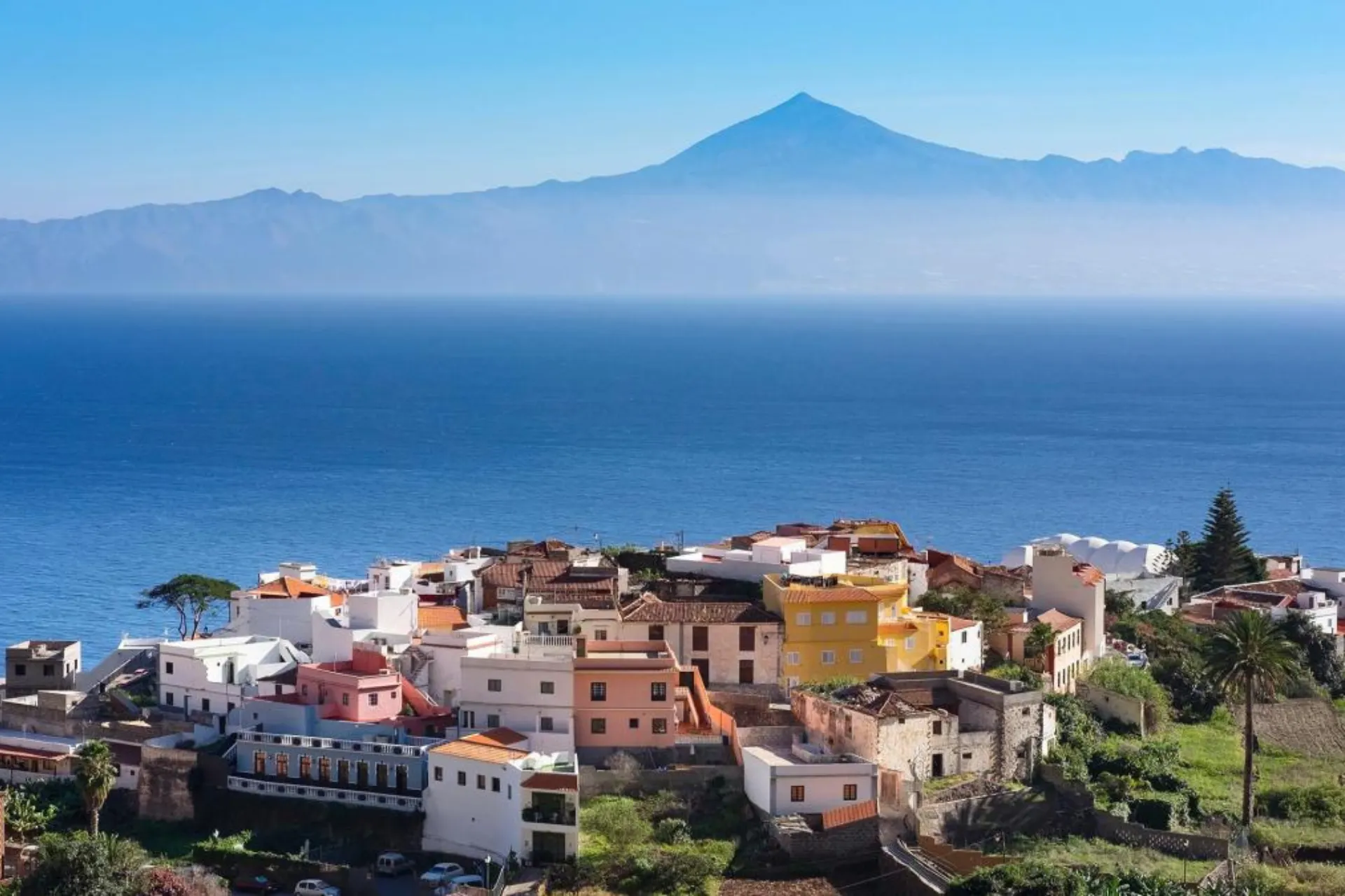 Uitzicht op een kleurrijk dorpje op La Gomera, met groene bergen en de zee in de achtergrond, Canarische Eilanden.