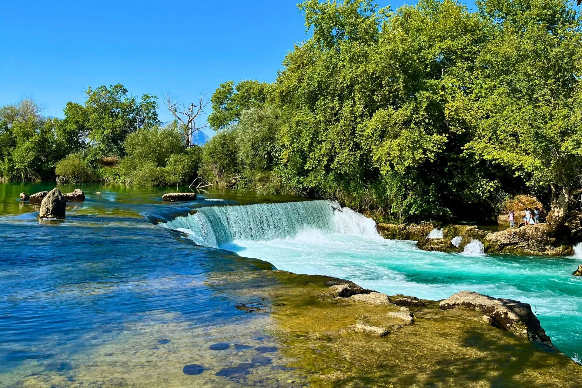 Panoramisch uitzicht op de beroemde watervallen van Manavgat nabij Side. Het snelstromende turquoise water stort zich over de rotsen en vormt een indrukwekkend natuurtafereel tussen de weelderige begroeiing. Een populaire attractie in de omgeving van Side en een geliefde stop tijdens excursies door de regio Manavgat.