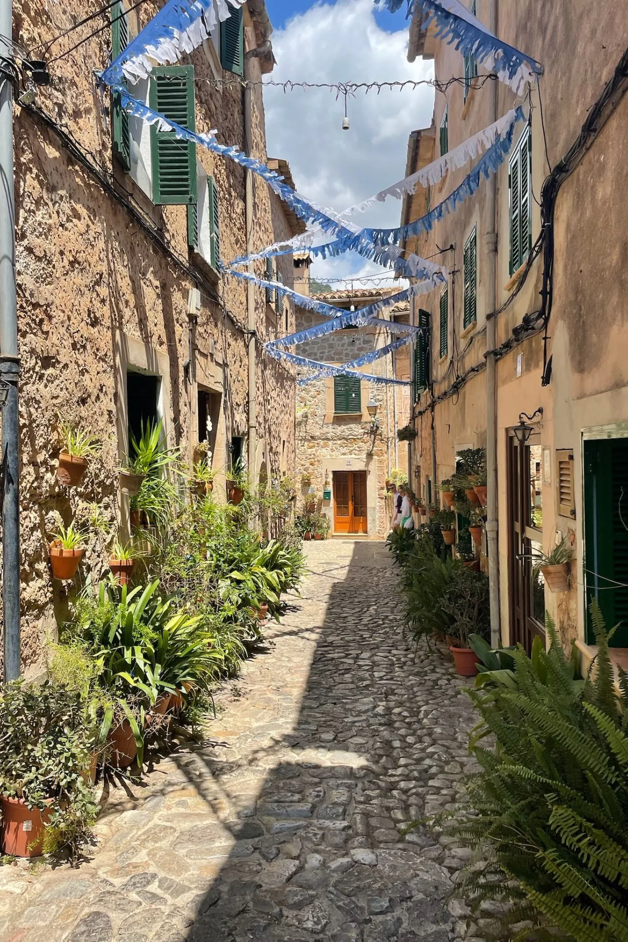 Blauwe zee met zeilboten, een rotsachtige kustlijn en een terrasrestaurant aan het water in Sa Calobra op Mallorca.