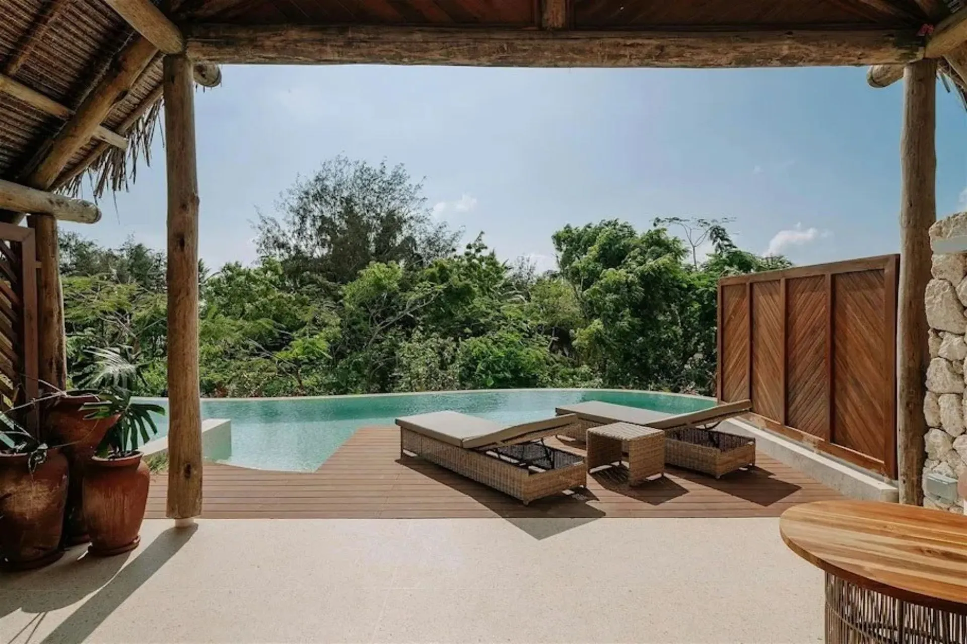 Privézwembad bij een villa van Matemwe Attitude op Zanzibar. Vanuit het overdekte terras kijk je uit over een groene tropische tuin terwijl je geniet van rust en privacy. De combinatie van natuurlijke materialen, luxe faciliteiten en een exclusieve ligging zorgt voor een bijzonder verblijf.