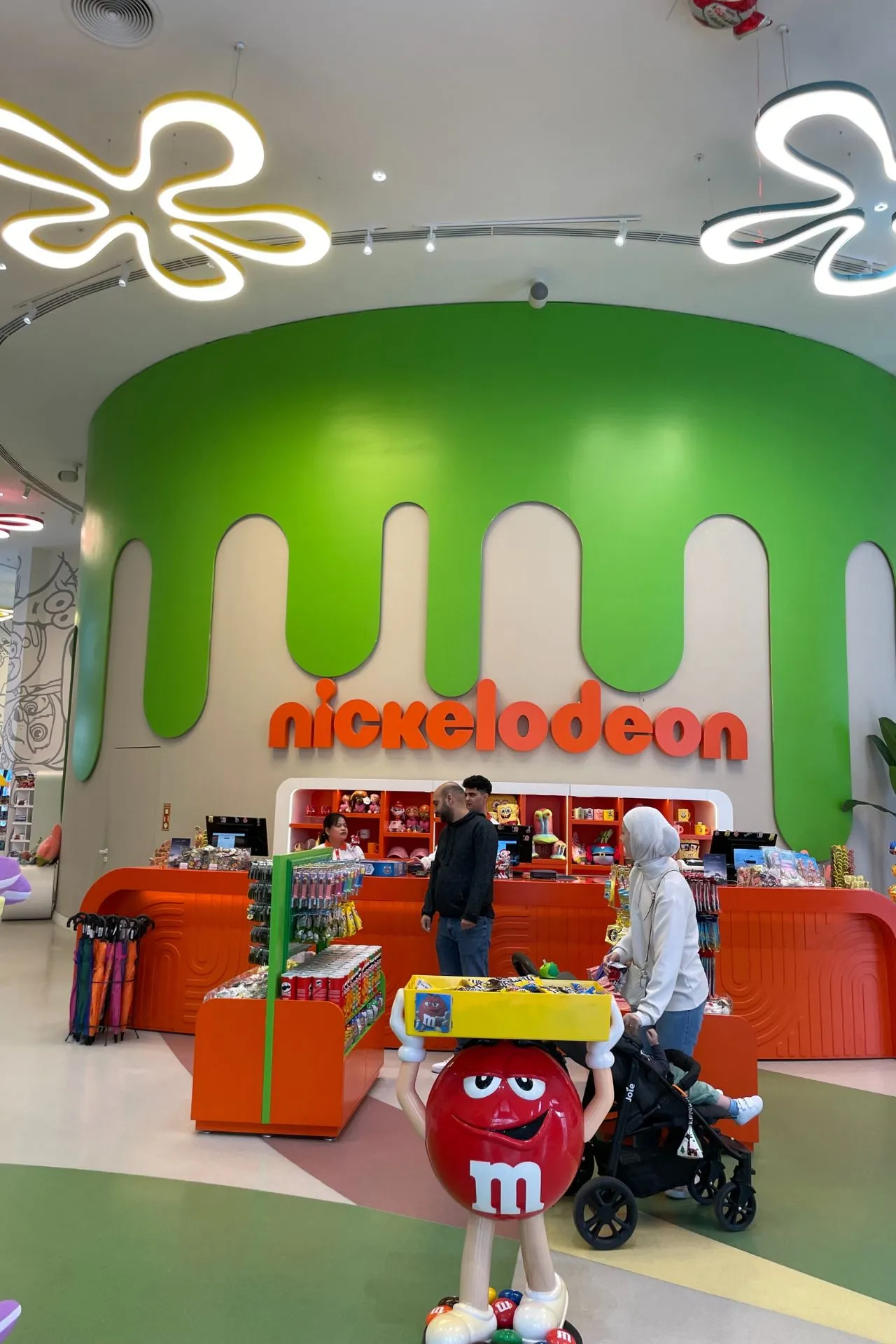 Winkelruimte met Nickelodeon-logo op een groene wand, kleurrijke displays en merchandise, inclusief M&M-figuur op de voorgrond.