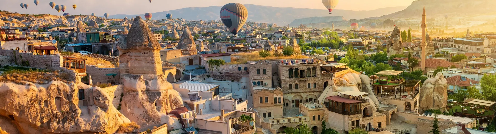 Luchtballonnen zweven boven de sprookjesachtige rotsformaties van Cappadocië tijdens zonsopgang.