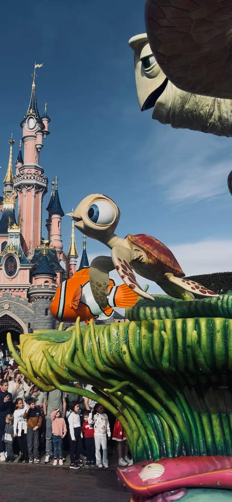 Disney Stars on Parade in Disneyland Parijs met kleurrijke Finding Nemo-figuren voor het iconische Doornroosje kasteel, omringd door een enthousiaste menigte