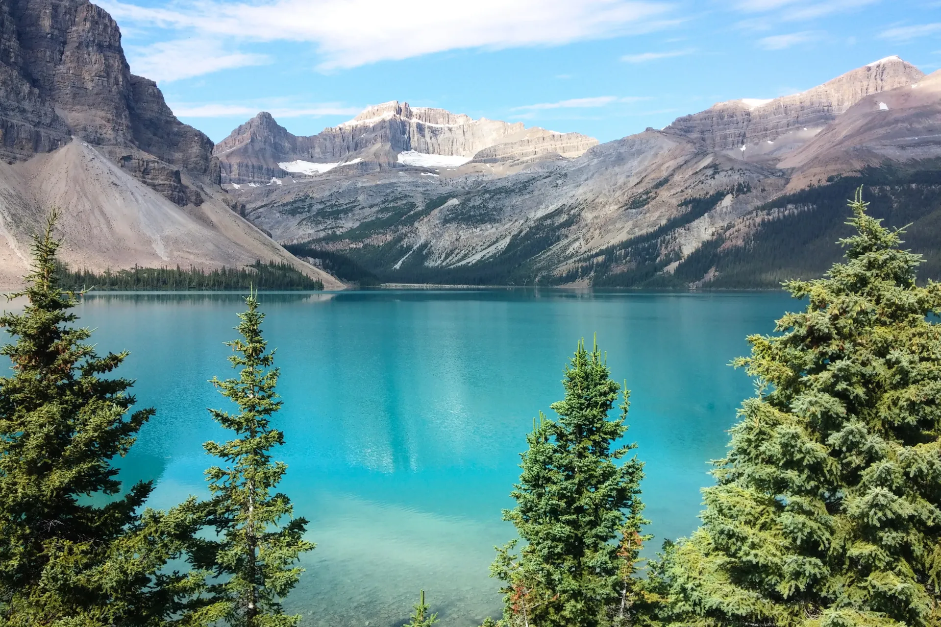 Helderblauw water van het Banff-meer in Canada, omringd door weelderig groen en majestueuze bergen.