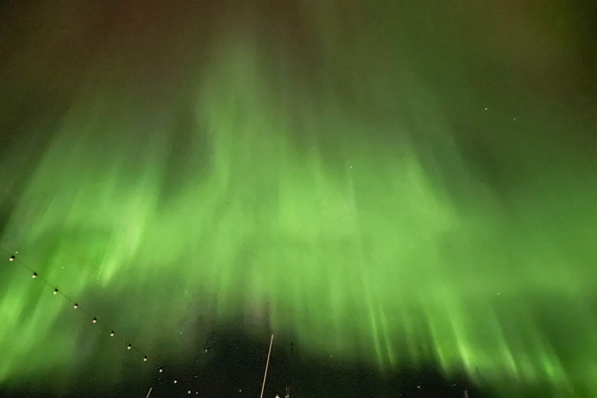 Het groene noorderlicht danst over de nachtelijke hemel in Zweden, terwijl het een magisch lichtspel creëert boven het besneeuwde landschap.