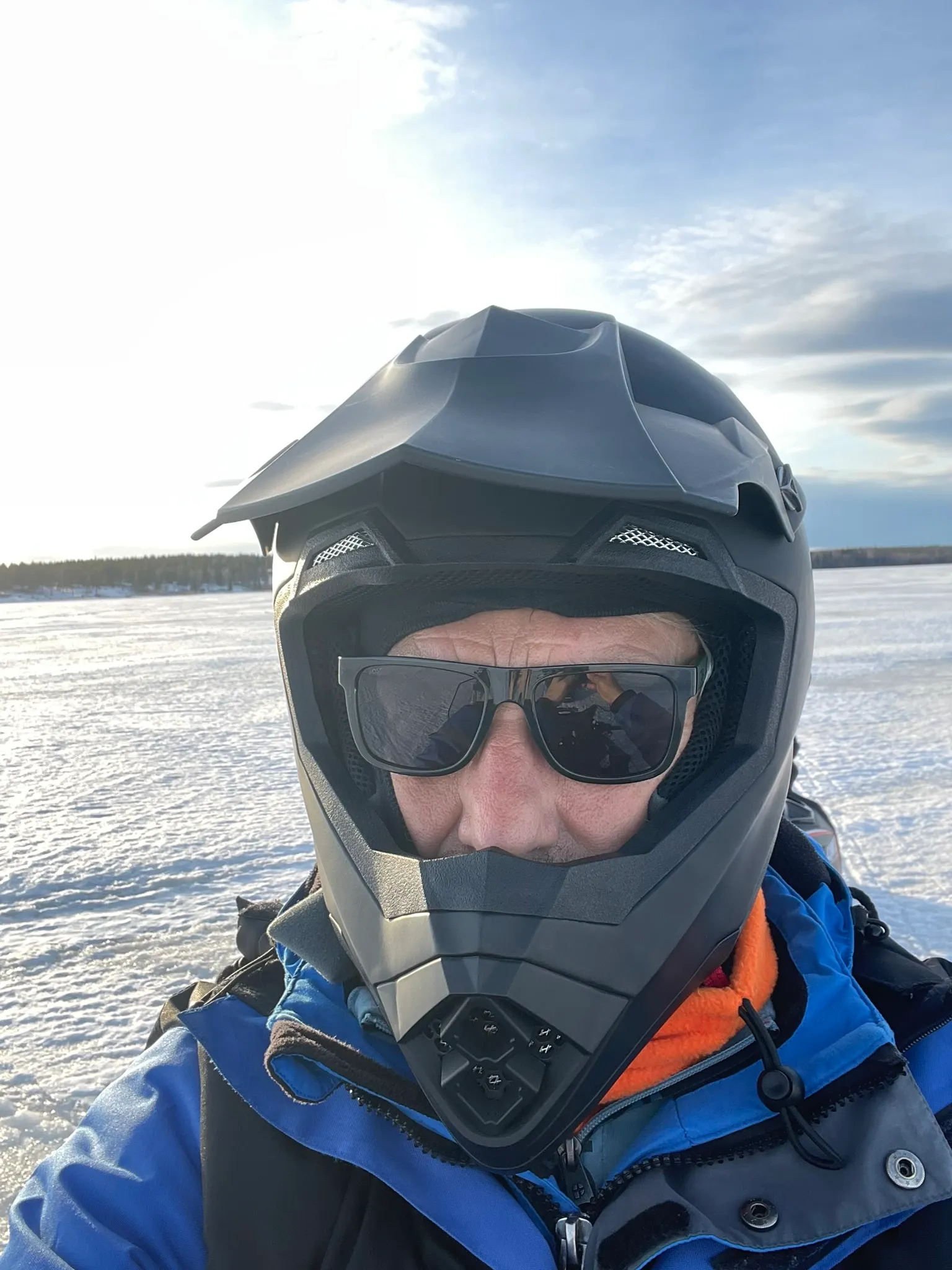 Man met zwarte helm op, goed ingepakt op een sneeuwscooter in Zweden.