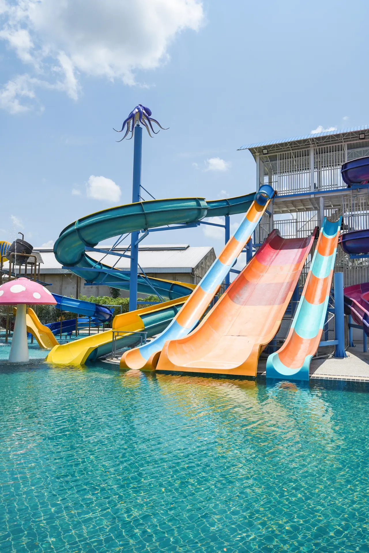 Kleurrijke waterglijbanen naast elkaar bij een resort, uitkomend in een groot zwembad, ideaal voor vakantieplezier.
