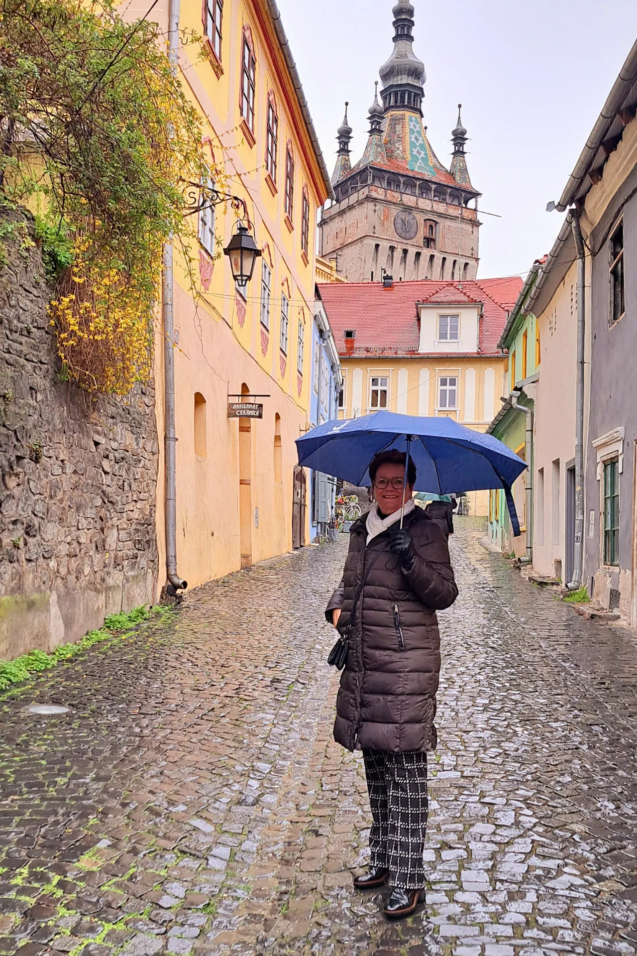Dame met paraplu loopt door een regenachtig steegje in Roemenië.