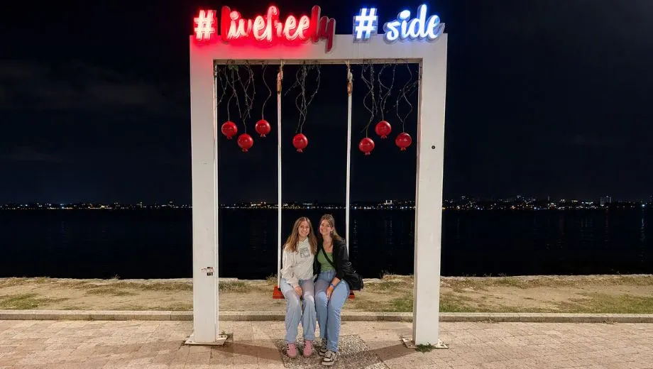Avond aan de boulevard van Side in Turkije met uitzicht over de Middellandse Zee. Op de voorgrond staat een verlichte fotolocatie met de tekst ‘#livelovely #side’, terwijl de kustlijn en de lichtjes van de stad zichtbaar zijn op de achtergrond. Side staat bekend om de sfeervolle boulevard, gezellige haven en mooie zonsondergangen aan de Turkse Rivièra.