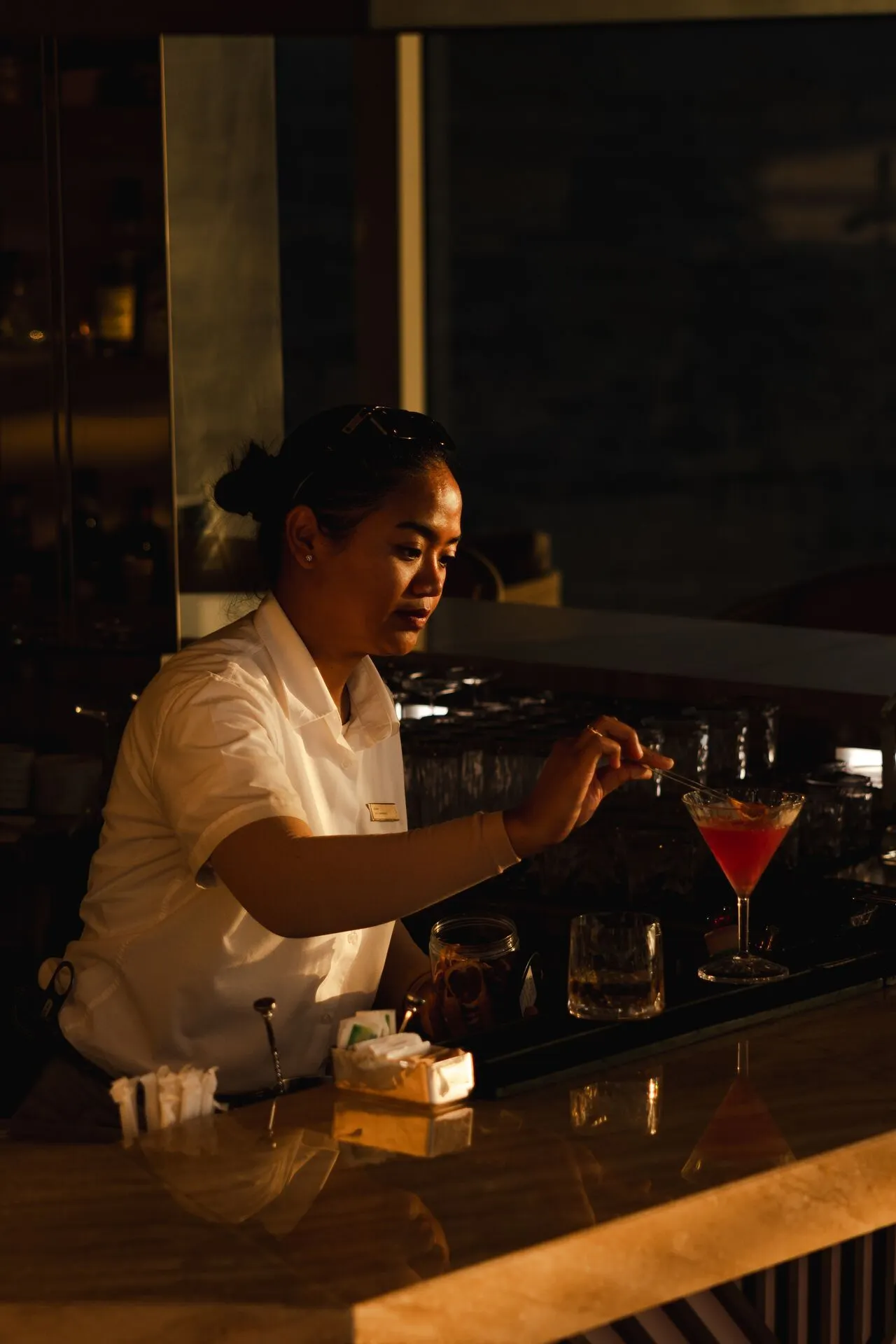 Luxe bar aan boord van een Explora Cruise schip, waar een verfijnde cocktail wordt bereid op een elegante houten bar met stijlvolle glazen en premium drankjes. Deze foto benadrukt de exclusieve service en culinaire beleving die Explora Journeys biedt tijdens een luxe cruisevakantie. Geniet van hoogwaardige cocktails, ontspannen sfeer en premium faciliteiten op zee, ideaal voor reizigers die comfort, gastronomie en luxe willen combineren tijdens hun cruise.