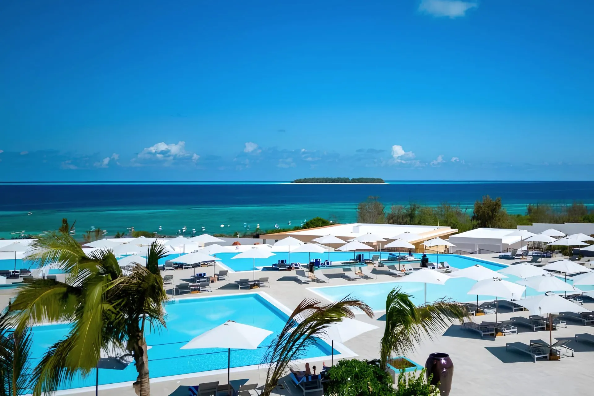 The Mora Zanzibar aan Muyuni Beach met meerdere luxe zwembaden, witte zonneterrassen en uitzicht over de turquoise Indische Oceaan. Dit vijfsterrenresort op Zanzibar combineert moderne architectuur, hoogwaardige faciliteiten en een prachtige ligging aan het strand voor een ontspannen luxe vakantie.