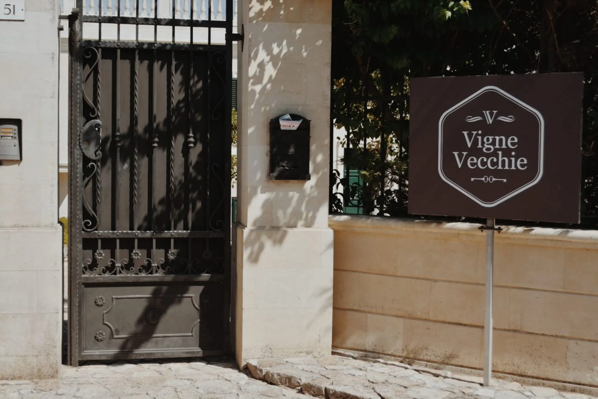 De ingang van Vigne Vecchie met een elegant smeedijzeren hek en een bord met de naam van de accommodatie.