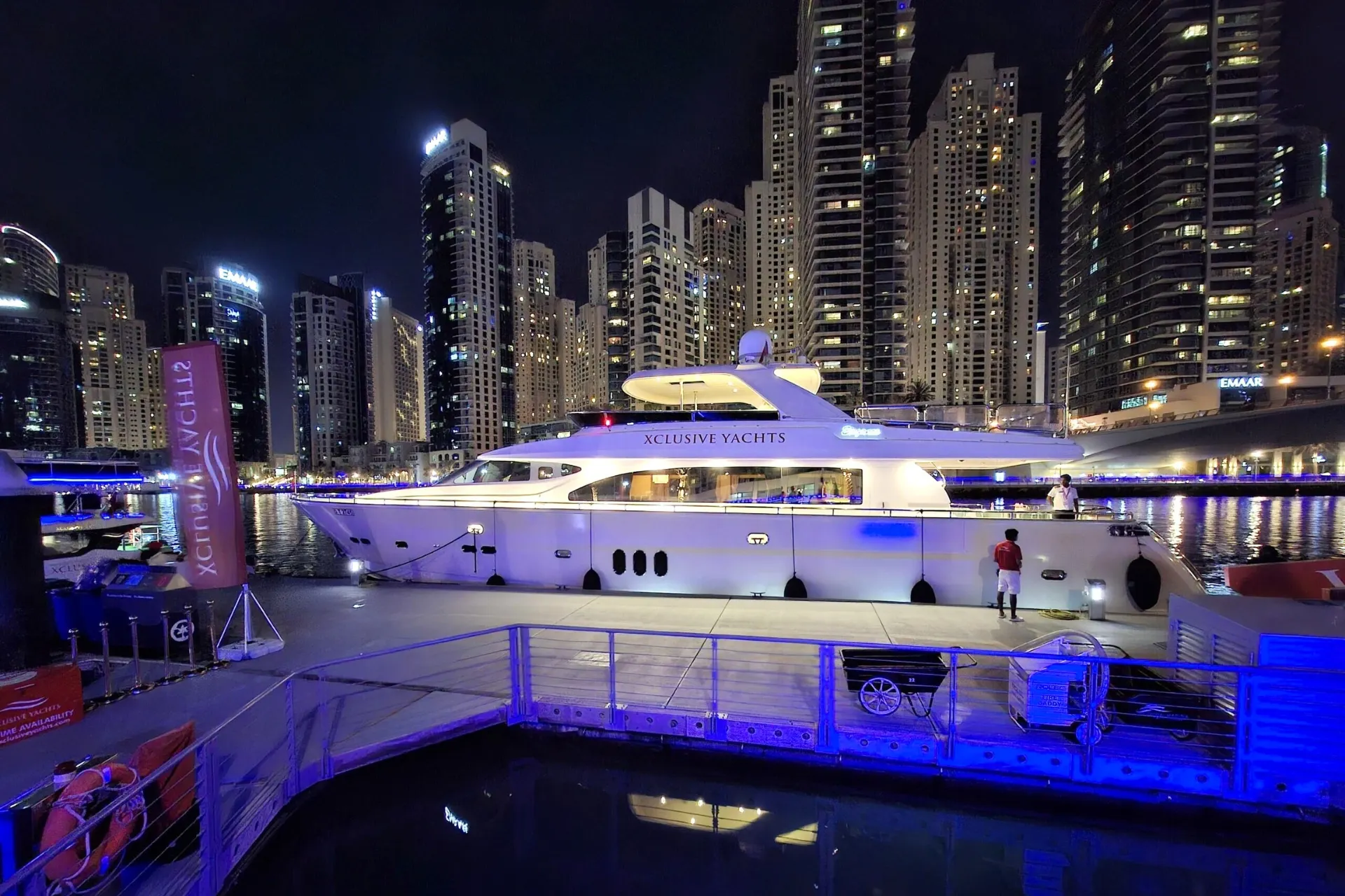 Dubai Marina haven in het donker met een luxe yacht op het water en de verlichte skyline op de achtergrond.