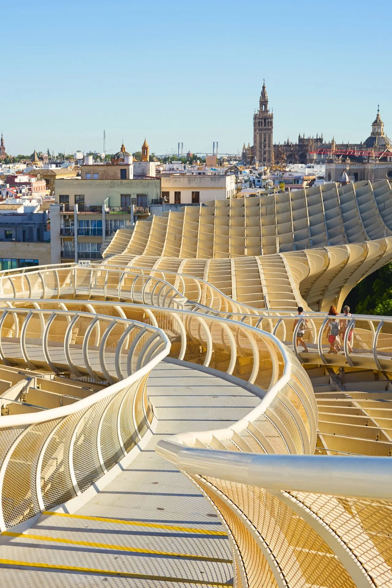 Uitzicht vanaf de wandelroute bovenop de Metropol Parasol in Sevilla. De golvende loopbrug slingert zich boven de stad uit, met uitzicht op historische gebouwen en de Giralda in de verte.