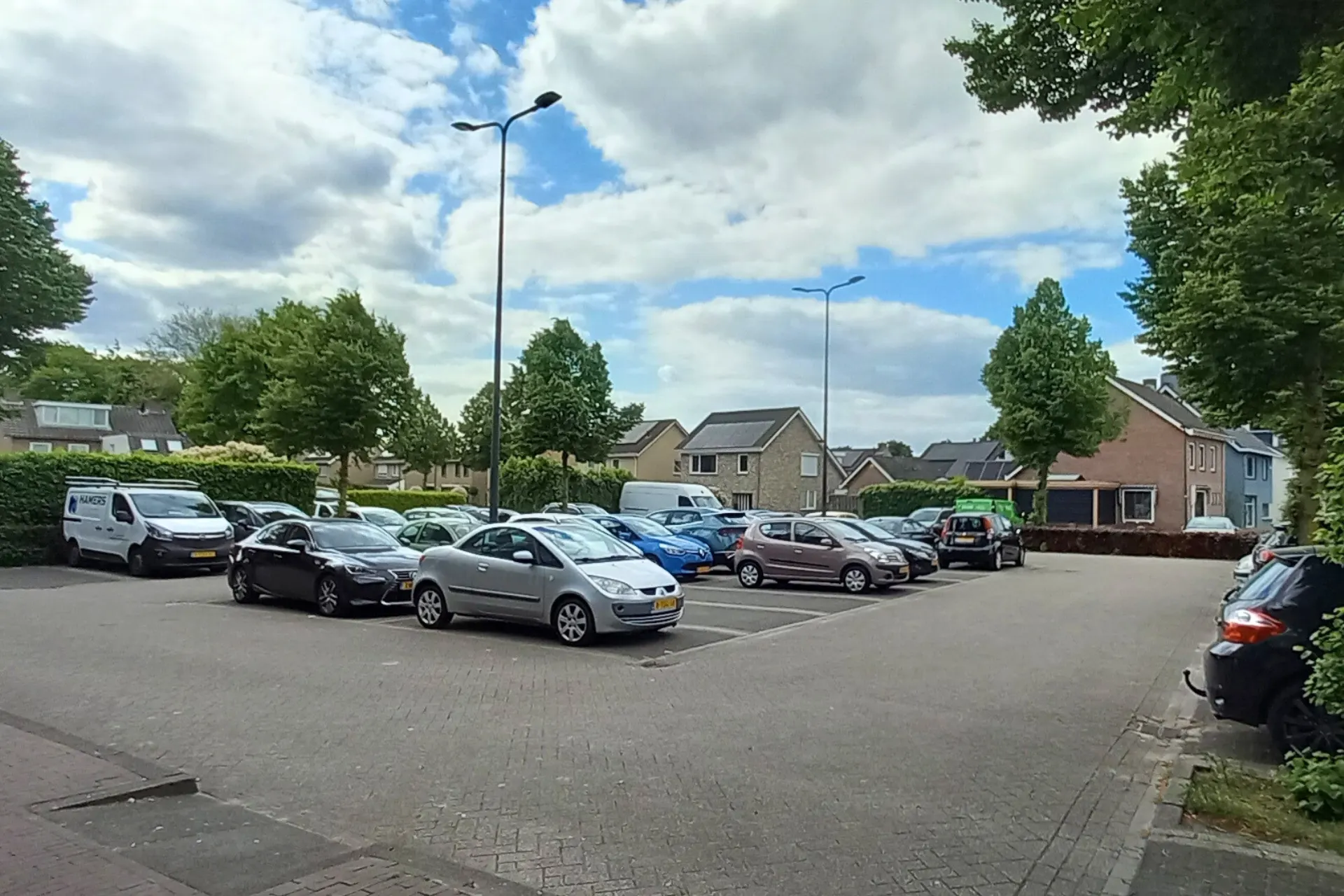 Parkeerplaats aan de Oude Dijk in Rosmalen, omringd door geparkeerde auto's en omliggende woonhuizen.