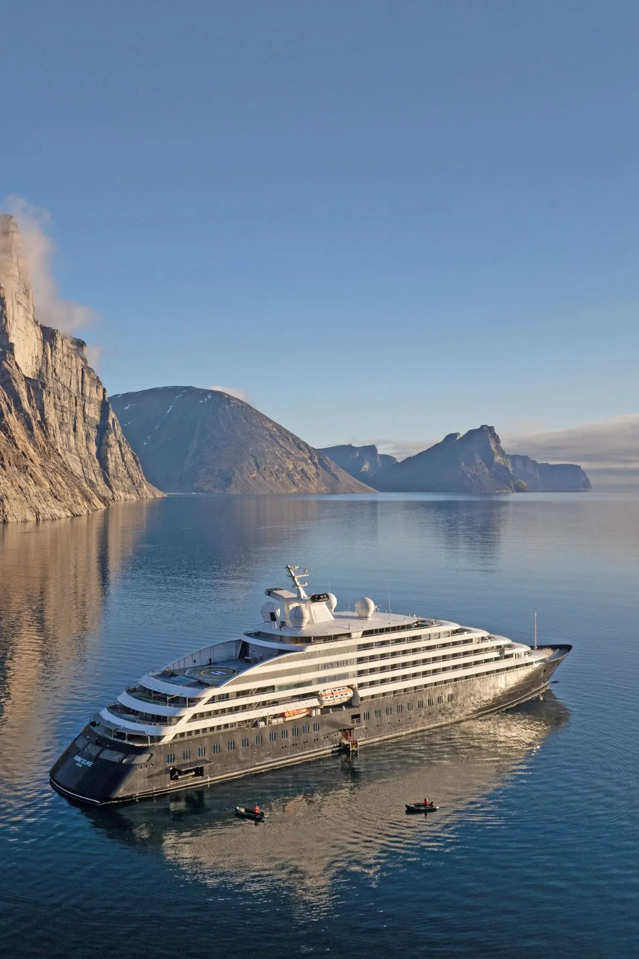 Een indrukwekkend expeditieschip ligt stil tussen hoge fjordwanden die weerspiegelen in het kalme water. De zachte ochtendzon en de ruige natuur versterken de sfeer van rust en exclusiviteit. Deze bestemming toont hoe een luxe cruise vakantie reizigers meeneemt naar spectaculaire, ongerepte gebieden zonder concessies te doen aan comfort. De ervaring is typerend voor luxe cruise maatschappijen die bijzondere routes varen.
