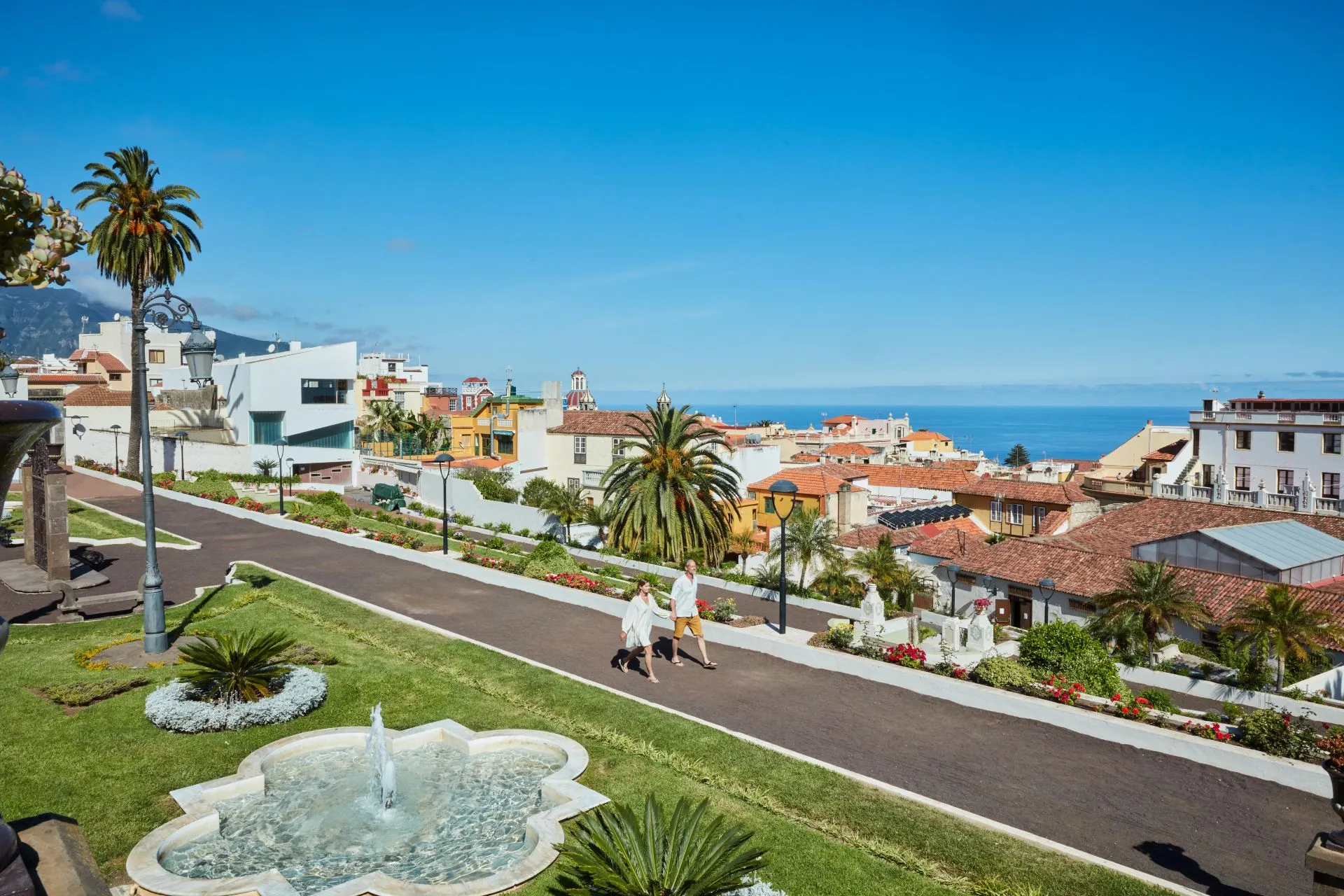 Uitzicht over Puerto de la Cruz in Noord‑Tenerife met kleurrijke huizen, groene tuinen en de Atlantische Oceaan op de achtergrond. Puerto de la Cruz laat perfect zien hoe stad en natuur samenkomen in Noord‑Tenerife. Deze levendige kustplaats combineert een historisch centrum, groene parken en uitzicht op de Atlantische Oceaan, wat het een populaire uitvalsbasis maakt voor een authentieke vakantie op Tenerife.

