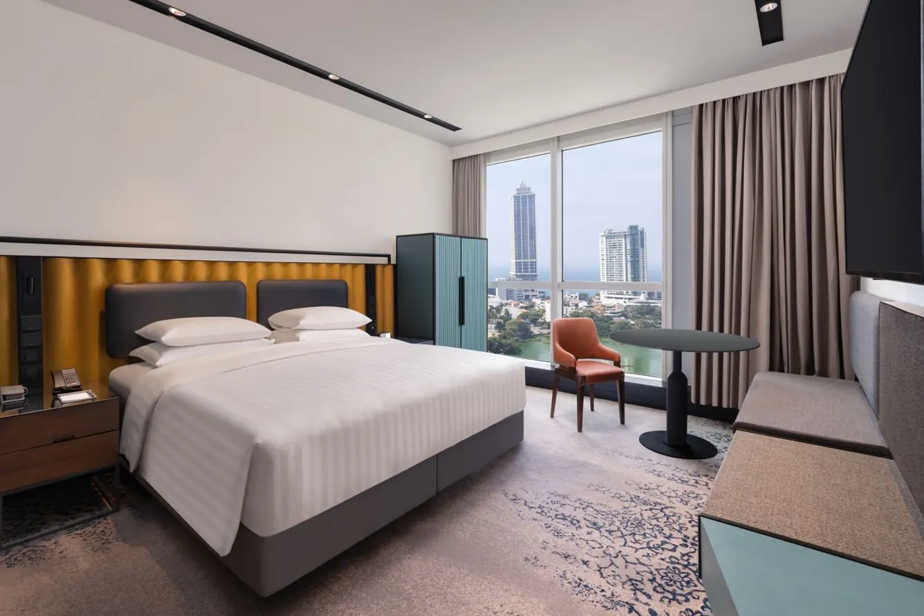Moderne hotelkamer bij Courtyard by Marriott Colombo met kingsize bed, panoramisch uitzicht over Colombo en de Indische Oceaan, en eigentijdse inrichting met warme kleuren en comfortabele voorzieningen.