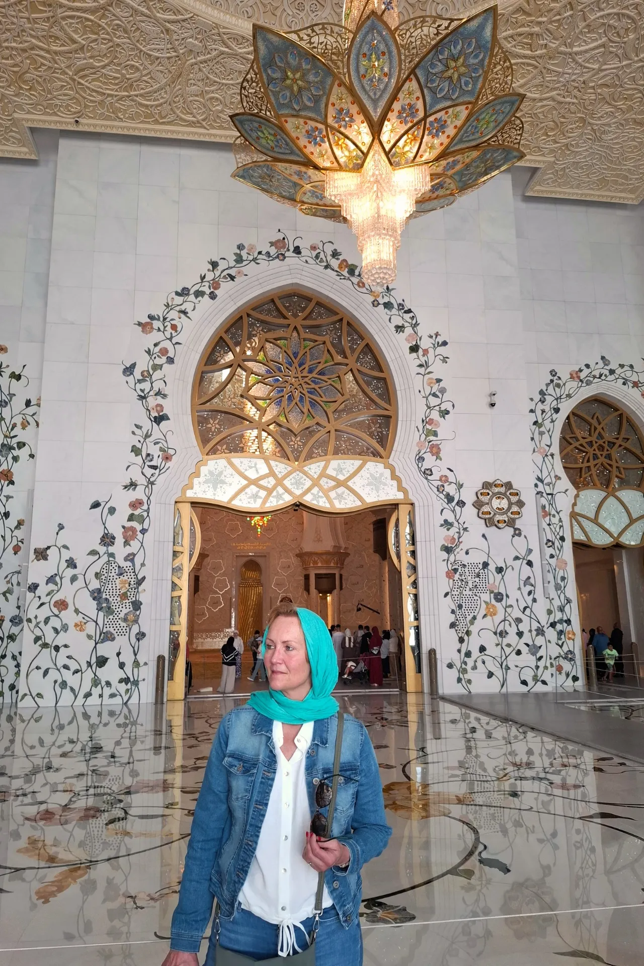 Astrid in de Sjeikh Zayed Moskee, met een blauwe hoofddoek, in respectvolle bewondering voor de pracht van de moskee.
