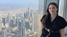 Reisadviseur Cassidy op grote hoogte in de Burj Khalifa, met een panoramisch uitzicht op de stad Dubai op de achtergrond.

