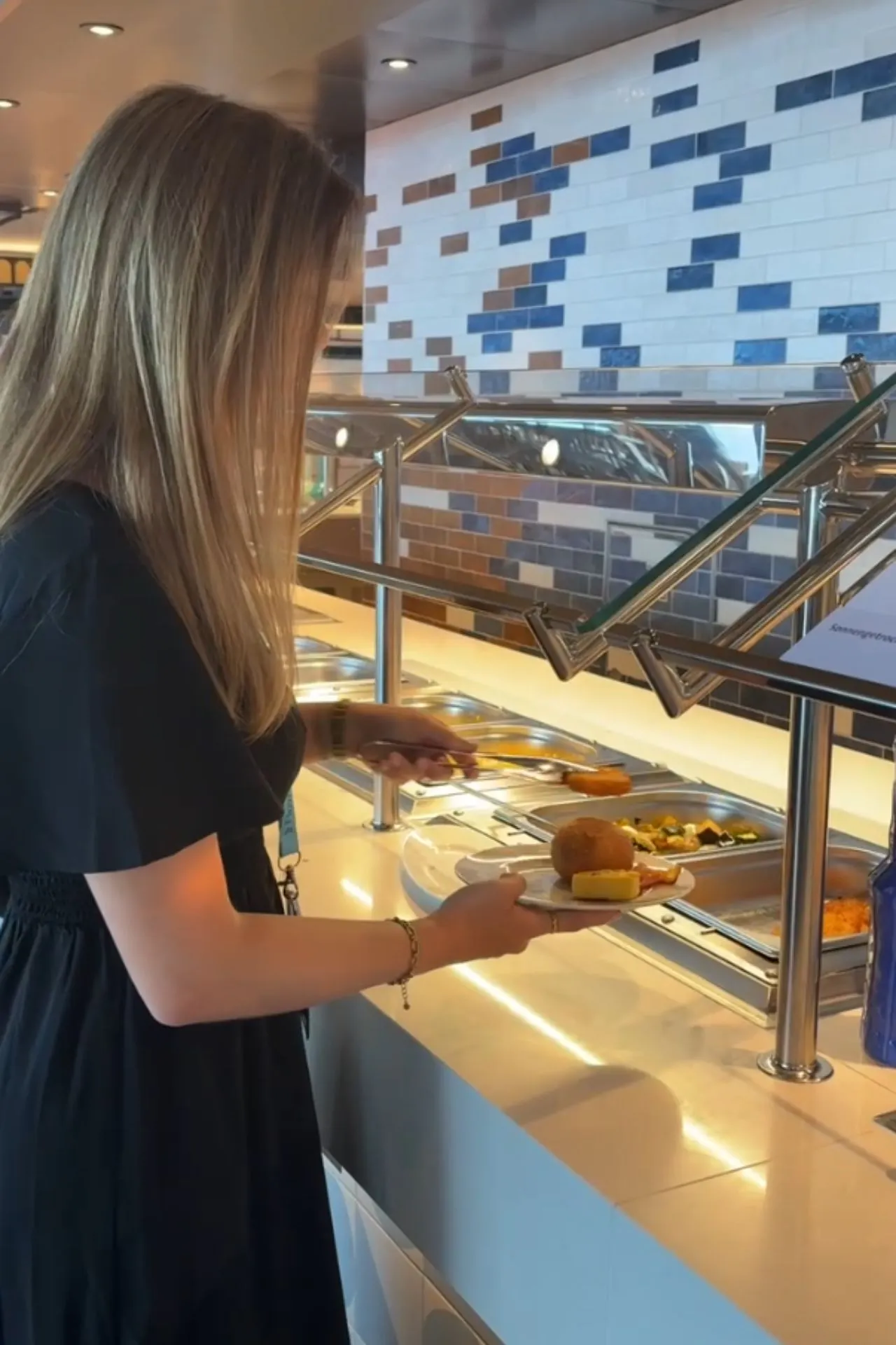 Martje maakt gebruik van het buffetrestaurant aan boord van de Mein Schiff Flow tijdens een cruisevakantie. De uitgebreide keuze aan warme en koude gerechten laat zien hoeveel maaltijden en culinaire mogelijkheden er inbegrepen zijn tijdens een cruise met Mein Schiff.