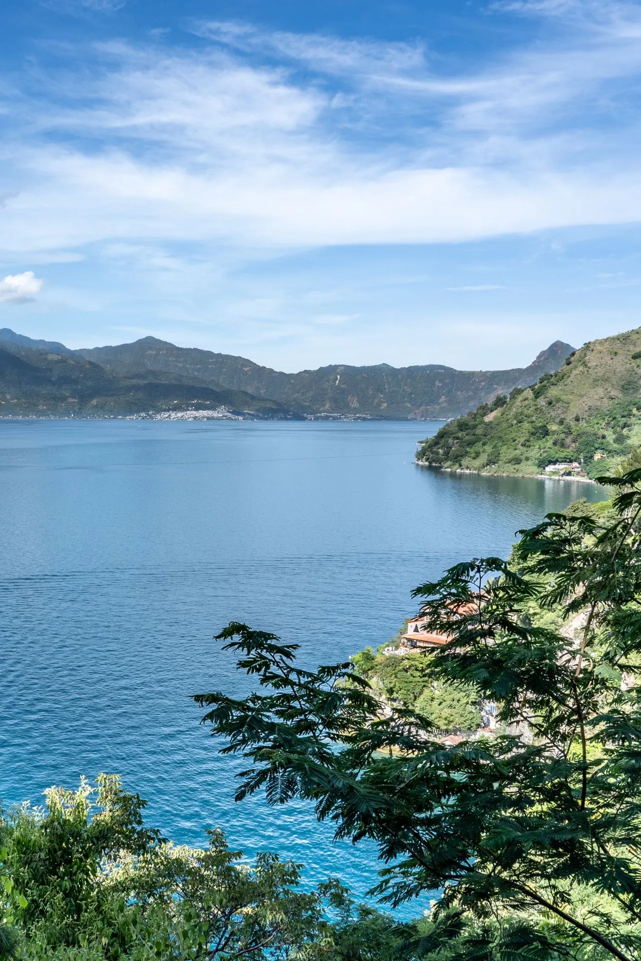 Panoramisch uitzicht over Lake Atitlán, omringd door vulkanen en groene heuvels in Guatemala.
