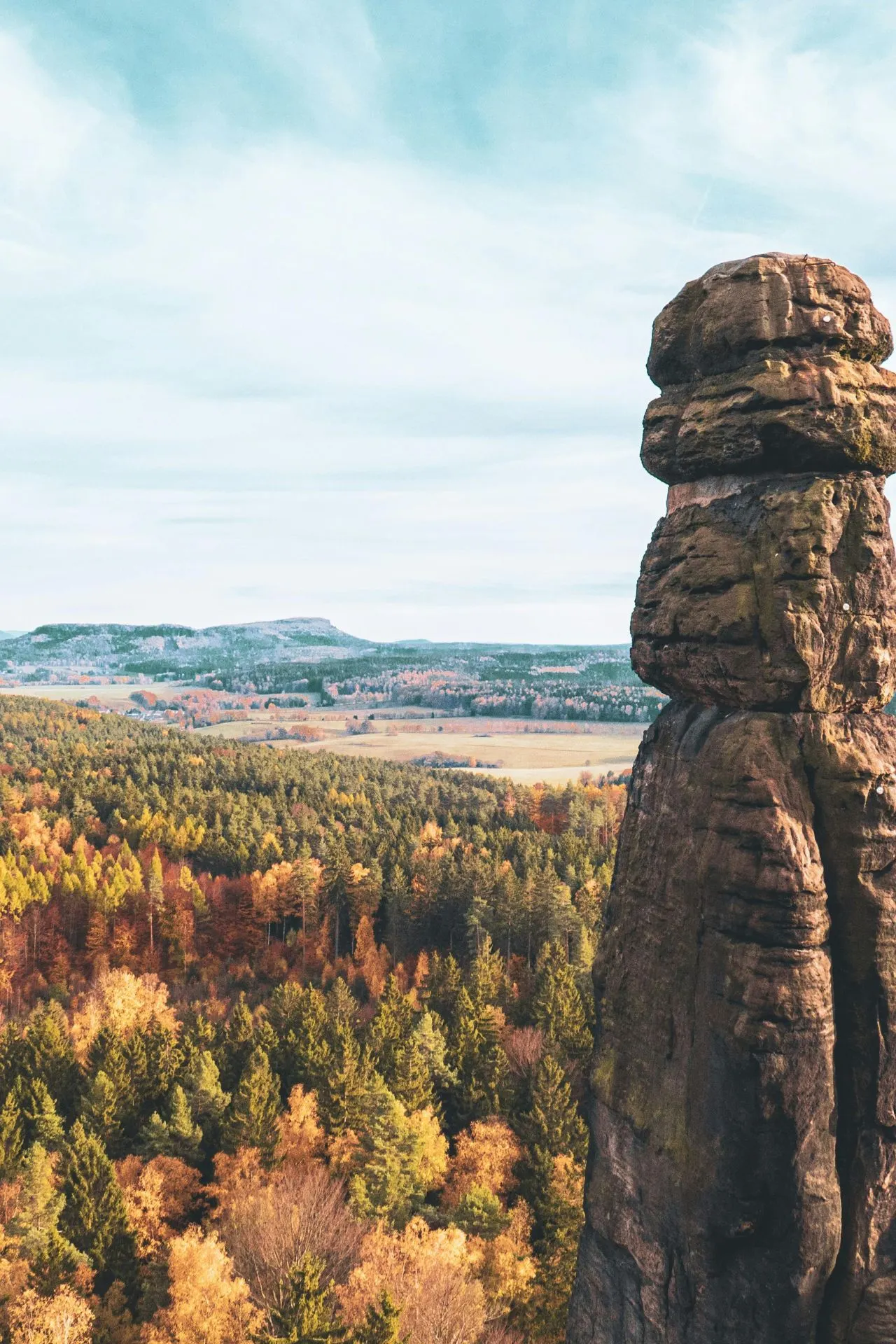 "Indrukwekkende zandsteenrots in Saksisch Zwitserland Nationaal Park, Duitsland, omringd door kleurrijke herfstbossen en een helderblauwe lucht. Deze bestemming is beroemd om zijn unieke rotsformaties, wandelroutes en panoramische uitzichten. Perfect voor een actieve vakantie in Duitsland, ontdek natuur, avontuur en rust in het Elbezandsteengebergte."