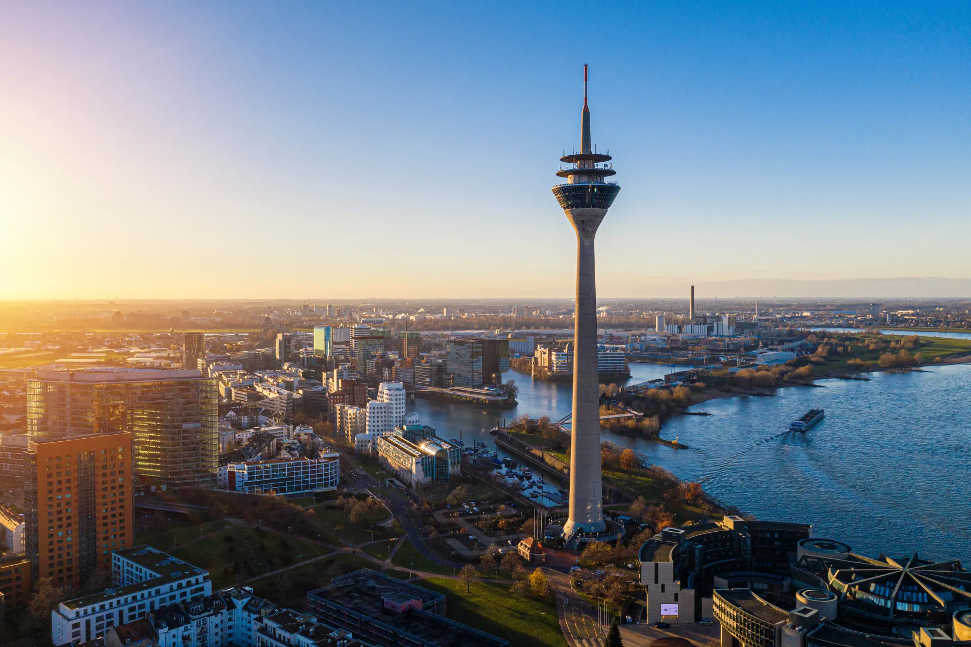 Panoramisch uitzicht op Düsseldorf met de Rheinturm en moderne architectuur, gefotografeerd bij zonsondergang.