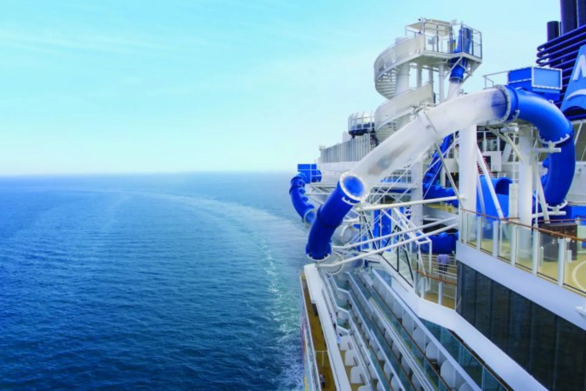 Waterglijbanen en outdoor faciliteiten op een modern Norwegian Cruise Line cruiseschip op open zee.
