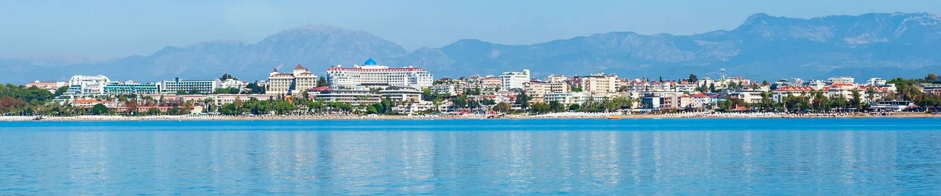 Panoramisch uitzicht op de kust van Side met moderne hotels, uitgestrekte stranden en de bergen van het Taurusgebergte op de achtergrond. Vanaf het water is goed te zien hoe natuur, zee en vakantievoorzieningen samenkomen. Side is een geliefde badplaats aan de Turkse Rivièra en een ideale uitvalsbasis voor excursies.