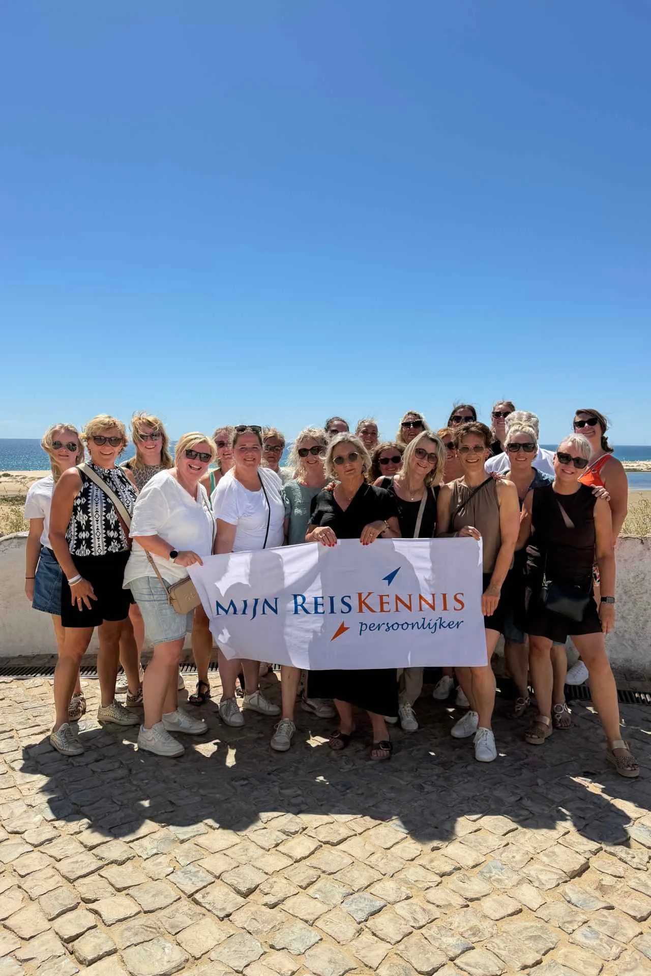 Deelnemers van een studiereis poseren aan de kust van de Algarve tijdens een inspirerende ontdekkingstocht door Portugal.