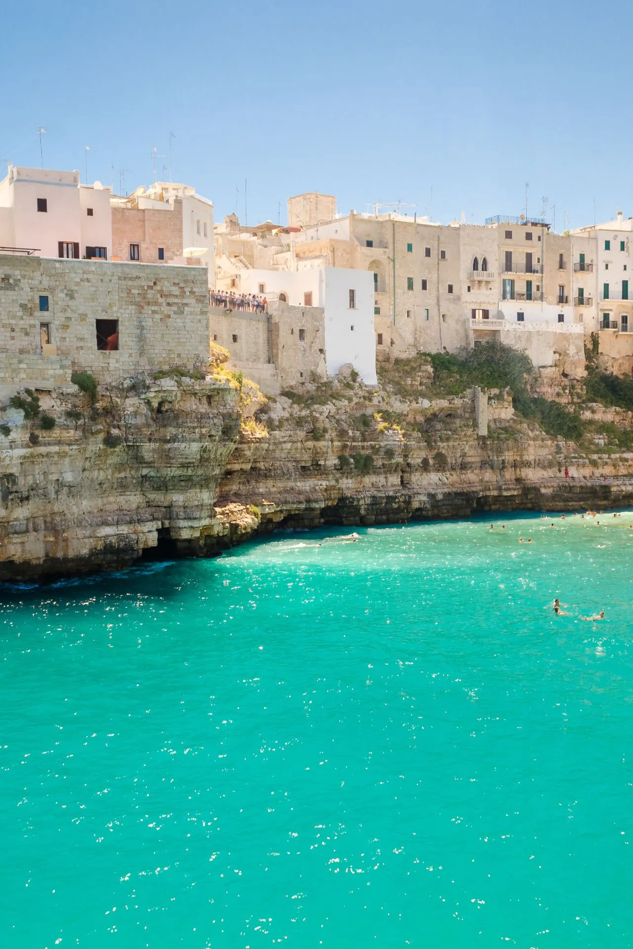 "Adembenemend uitzicht op Polignano a Mare, Puglia, Italië, met turquoise water van de Adriatische Zee, imposante witte kalkstenen kliffen en historische gebouwen bovenop de rotsen. Deze kustplaats is beroemd om zijn stranden, grotten en spectaculaire uitzichten. Perfect voor een zomervakantie in Zuid-Italië, geniet van zon, zee, cultuur en heerlijke Italiaanse keuken in een idyllische setting."